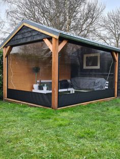 a small backyard shed with a couch in the corner and green grass on the ground