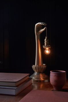 a table with a lamp and some books on it, next to a candle holder