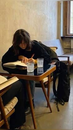 a woman sitting at a table writing in a book