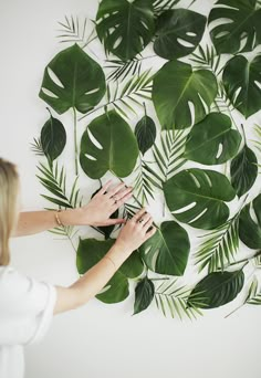 a woman is painting a wall with green leaves on it and the words fashion, fashion and lace written in front of her