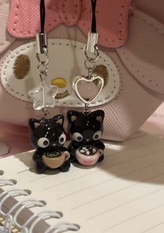 two little black and white cats are hanging from the keychains on a notepad