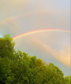 two rainbows in the sky over some trees