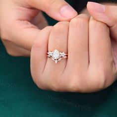 a woman's hand holding an engagement ring with three stones on it, and the other