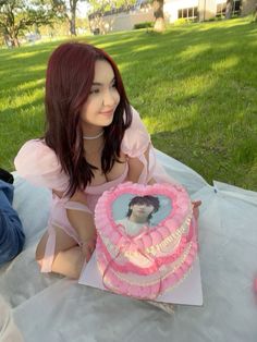 a woman sitting on the ground with a cake in front of her