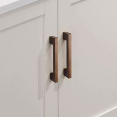 two wooden handles on the side of a white cabinet