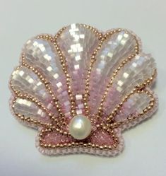 a pink and white brooch with pearls on it's back end, in the shape of a shell