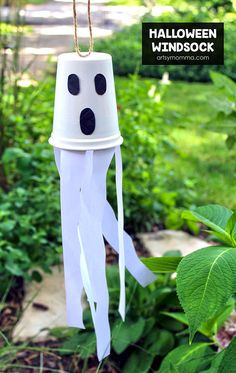 a white paper lantern hanging from a rope in the grass with black dots on it