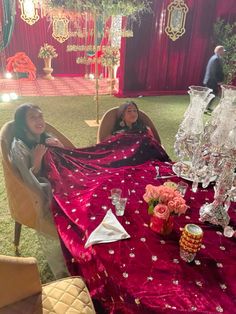 two women sitting at a table covered in red cloths