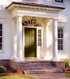 a white house with columns and a green door