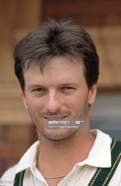 a man wearing a green and white sweater smiling at the camera with his eyes closed