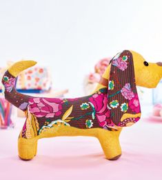 a dog made out of fabric sitting on top of a pink tablecloth covered table