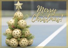 a christmas tree made out of balls on a tennis court with the words merry christmas