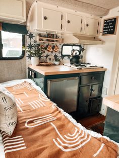 a kitchen area with a stove, microwave and sink in the back side of a camper