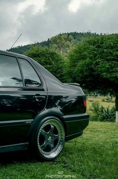 a black car parked on top of a lush green field