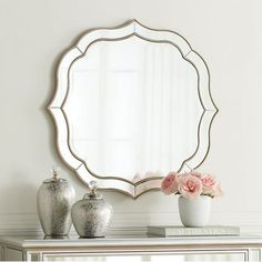 a mirror sitting on top of a dresser next to vases