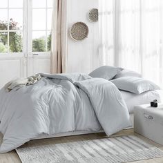 a bed with white sheets and pillows in a room next to a rug on the floor