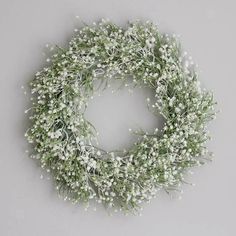 a white wreath with baby's breath hanging on the wall