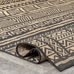 a black and beige rug on the floor with an interesting design in it's center