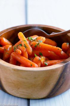 a wooden bowl filled with carrots on top of a table