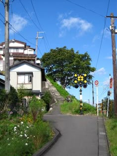 an empty street with power lines above it and houses on the hill in the background