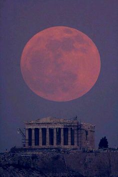 the full moon is seen over an old building