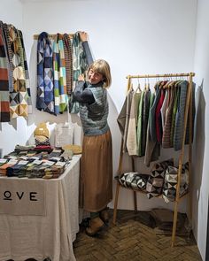 a woman standing in front of a table with clothing on it