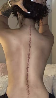 the back of a woman's body with writing on it and her hands behind her head