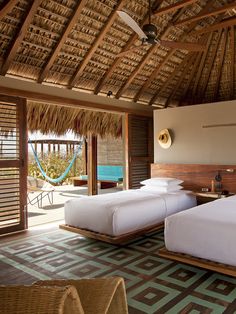 a hotel room with two beds and a hammock hanging from the rafter