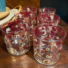 four red glass cups sitting on top of a wooden table