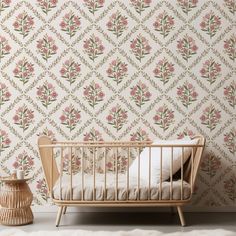 a baby's crib in front of a floral wallpaper with pink flowers