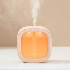 an orange and white humider sitting on top of a table with steam coming out of it