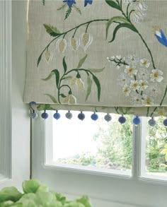 the window is decorated with blue and white flowers on it's valance,