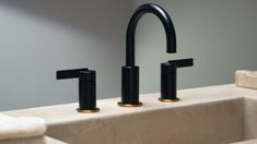 two black faucets sitting on top of a sink in a bathroom next to towels