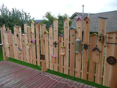 a fence made out of wooden boards with birdhouses on the top and birds in the bottom