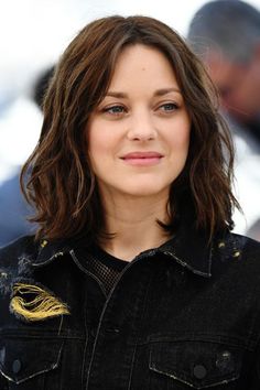 a close up of a person wearing a jean jacket and looking at the camera with a smile on her face