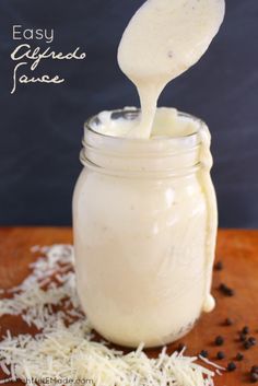 a spoon full of cheese being poured into a jar