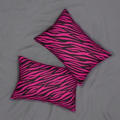 two pink and black zebra print pillows on a gray bed sheet with grey sheets in the background