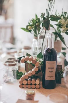 a bottle of wine sitting on top of a table next to some corks and flowers