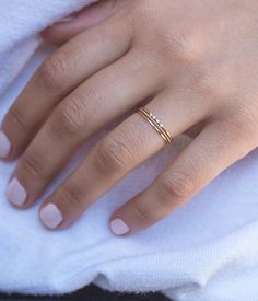 a woman's hand with a gold ring on top of her left hand and a white towel in the background