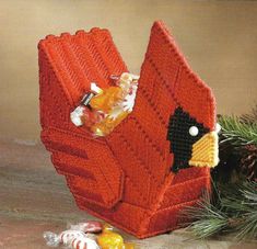 a knitted bird sitting on top of a wooden table next to pine cones and candy