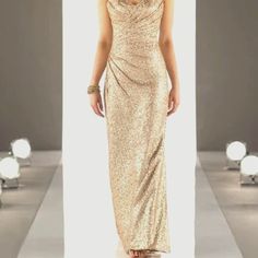 a woman in a gold dress walking down a runway