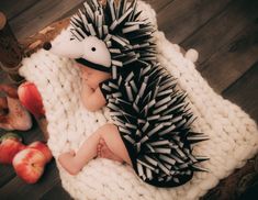 a baby laying on top of a blanket next to apples