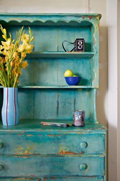 a blue dresser with yellow flowers in a vase