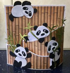 a card with pandas on it and bamboo sticks in the middle, cut out to look like they are playing together