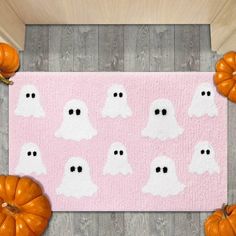 a pink rug with white ghost faces and pumpkins on the floor next to it