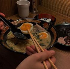 someone is eating ramen with chopsticks on the table