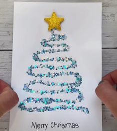 someone holding up a card with a christmas tree on it and the words merry christmas