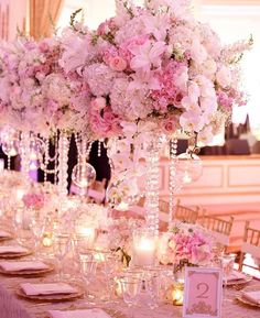 the table is set with pink flowers and candles for an elegant wedding reception or special event