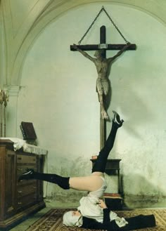 a woman laying on the ground in front of a crucifix