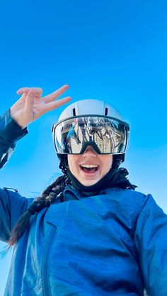 a woman wearing goggles and holding her hands up in the air